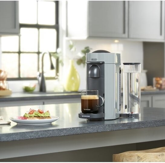 nespresso coffee and espresso maker with a cup of coffee on a counter