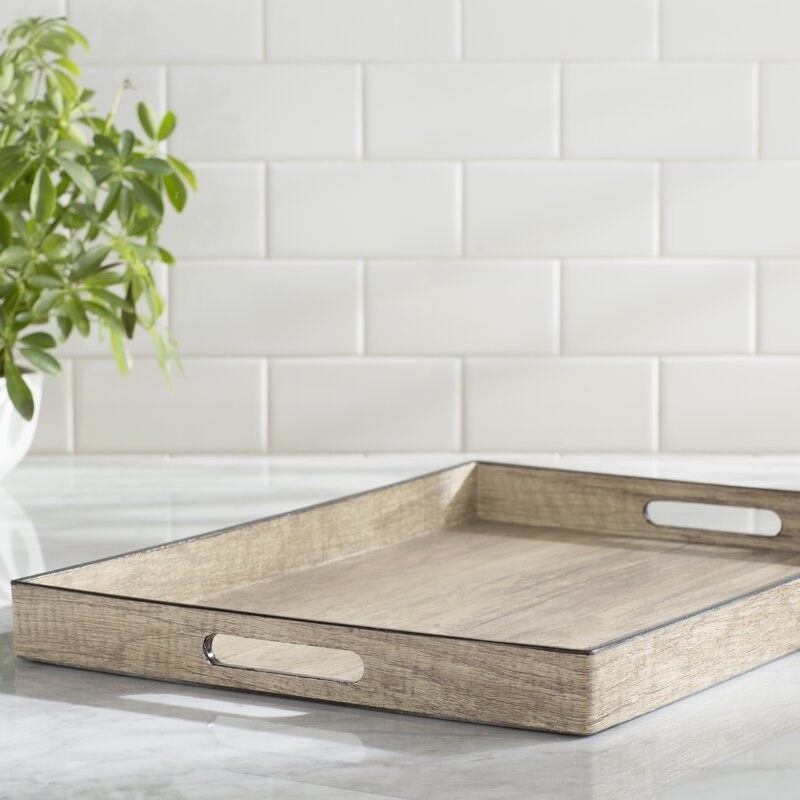 wood colored decorative rectangular tray with handles on a counter