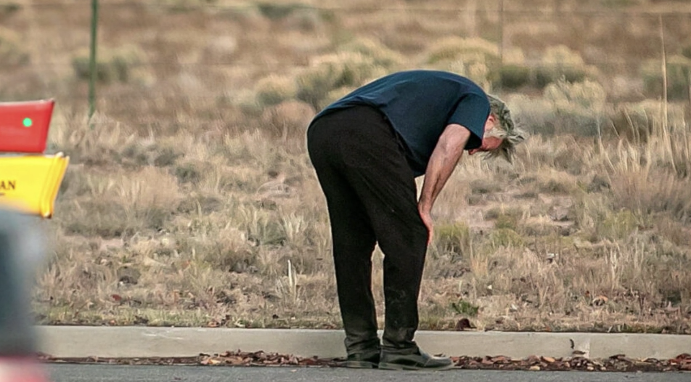 Alec bending down with anxiety at the film set