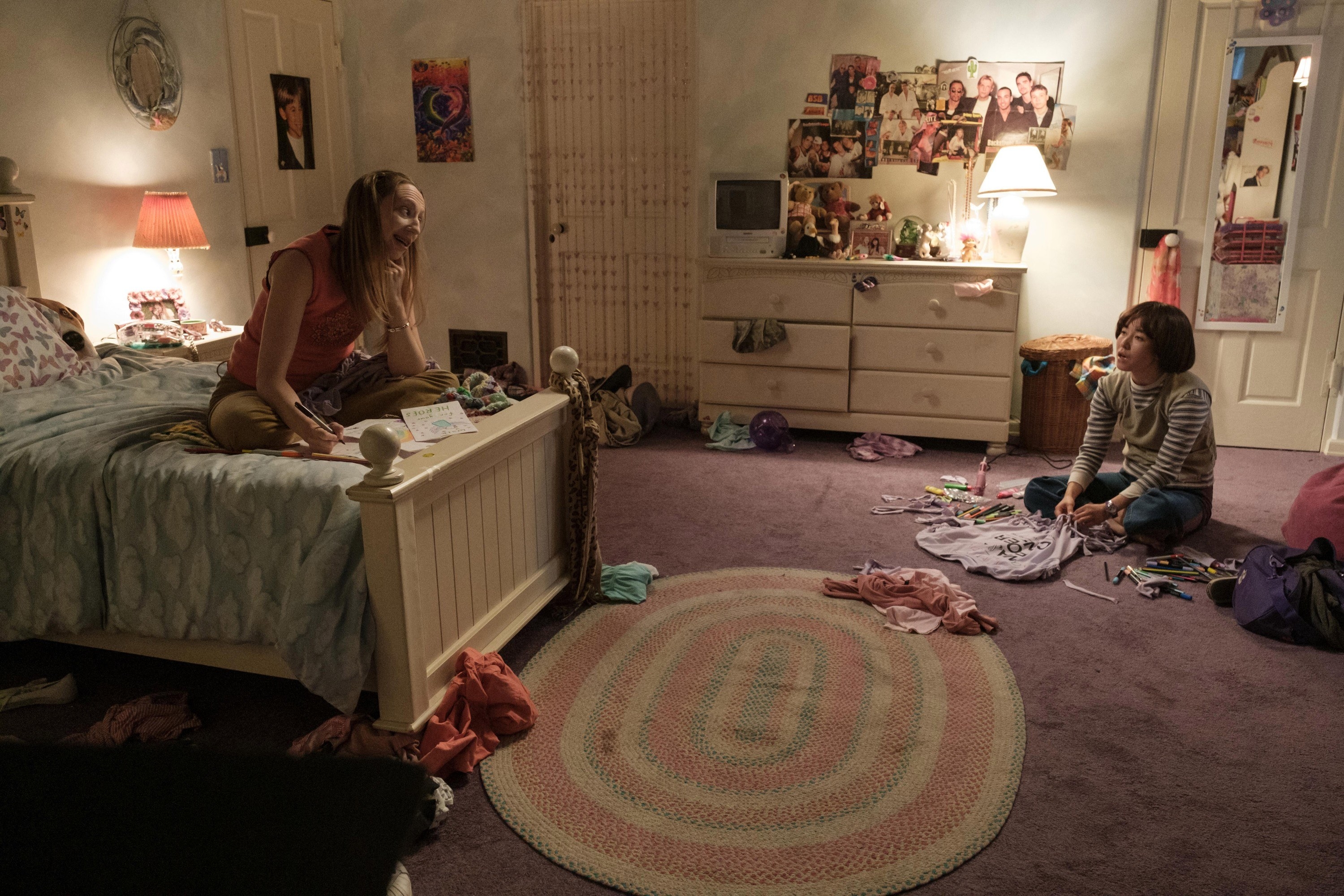 Anna taunts Maya from her bed while Maya protests from the floor
