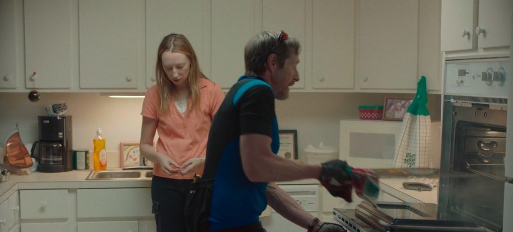 Anna looks distressed while her dad removes a pan from the oven