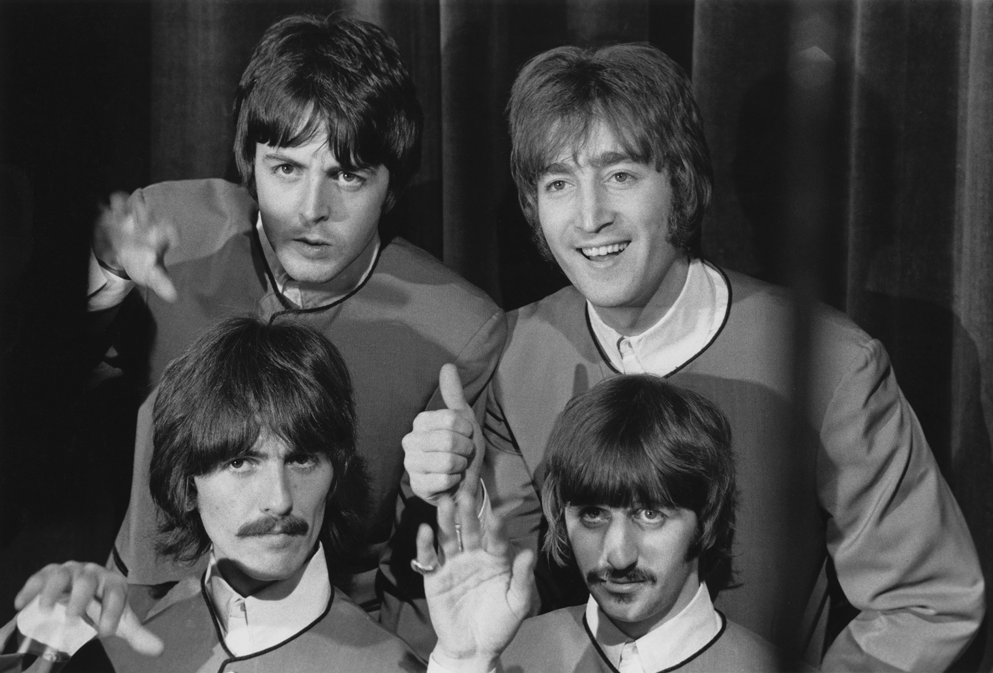 the four beatles wave and give the camera a thumbs up in matching outfits