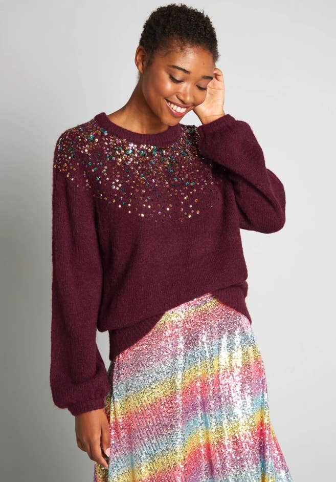 model wearing a red sweater with sequins on it