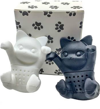 The white and black cat-shaped tea diffusers with a little box