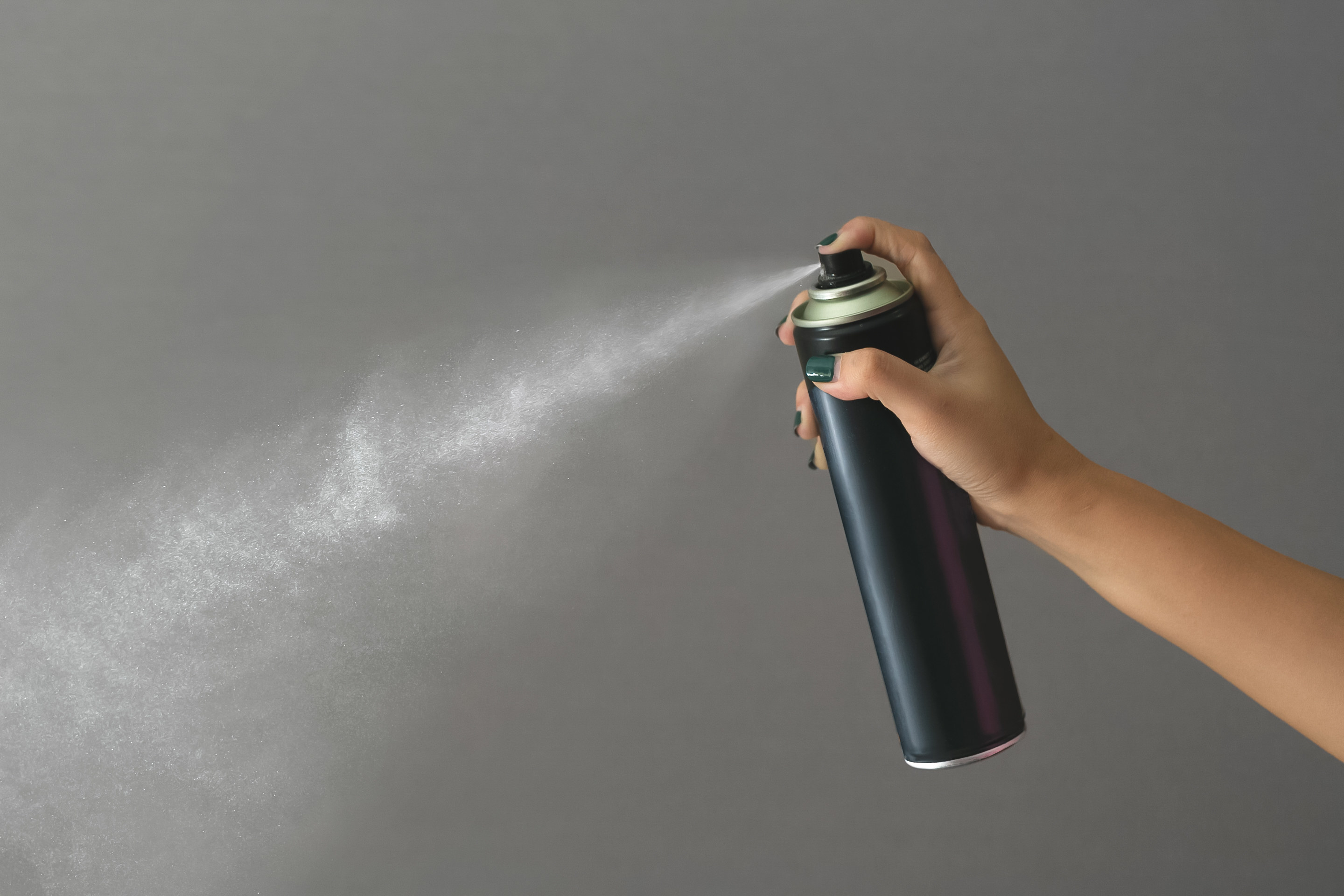 A black can of hairspray being sprayed