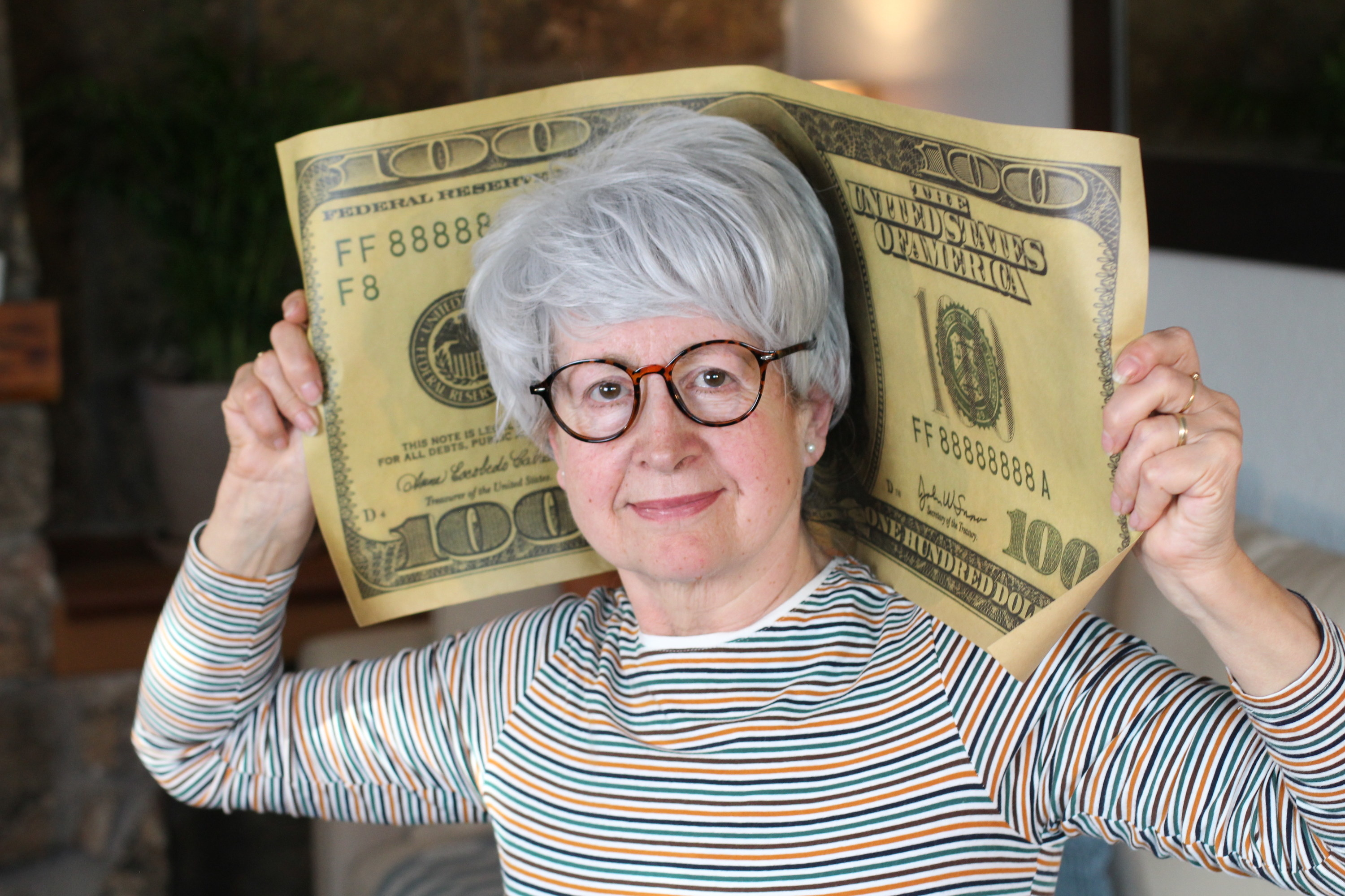 Senior woman holding gigantic dollar bill
