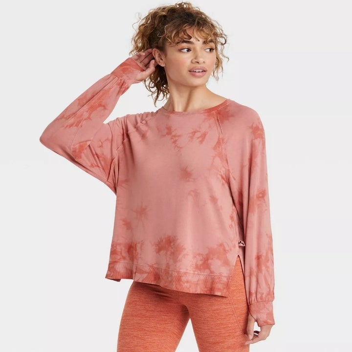 A model wearing a lightweight round neck sweater in light red tie dye