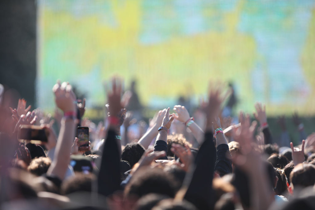 People in the crowd with their hands in the air during a performance