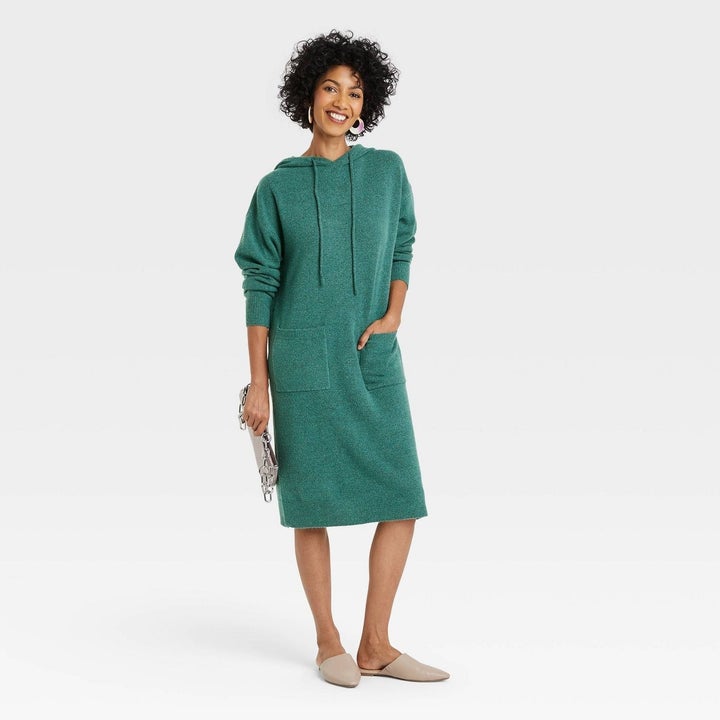 model in a midi length green hoodie sweater dress with two square front pockets