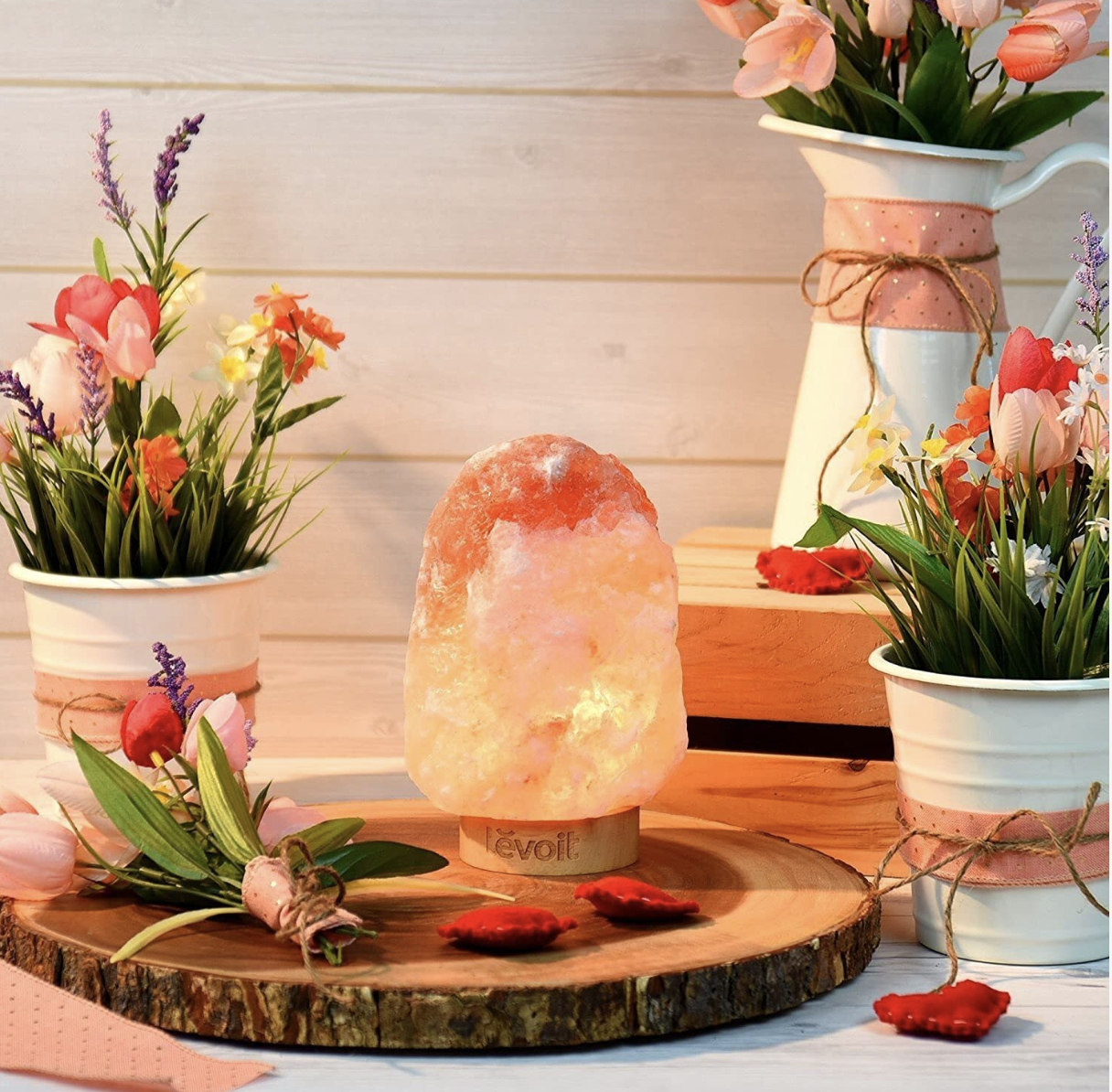 A salt lamp on a counter surrounded by flowers