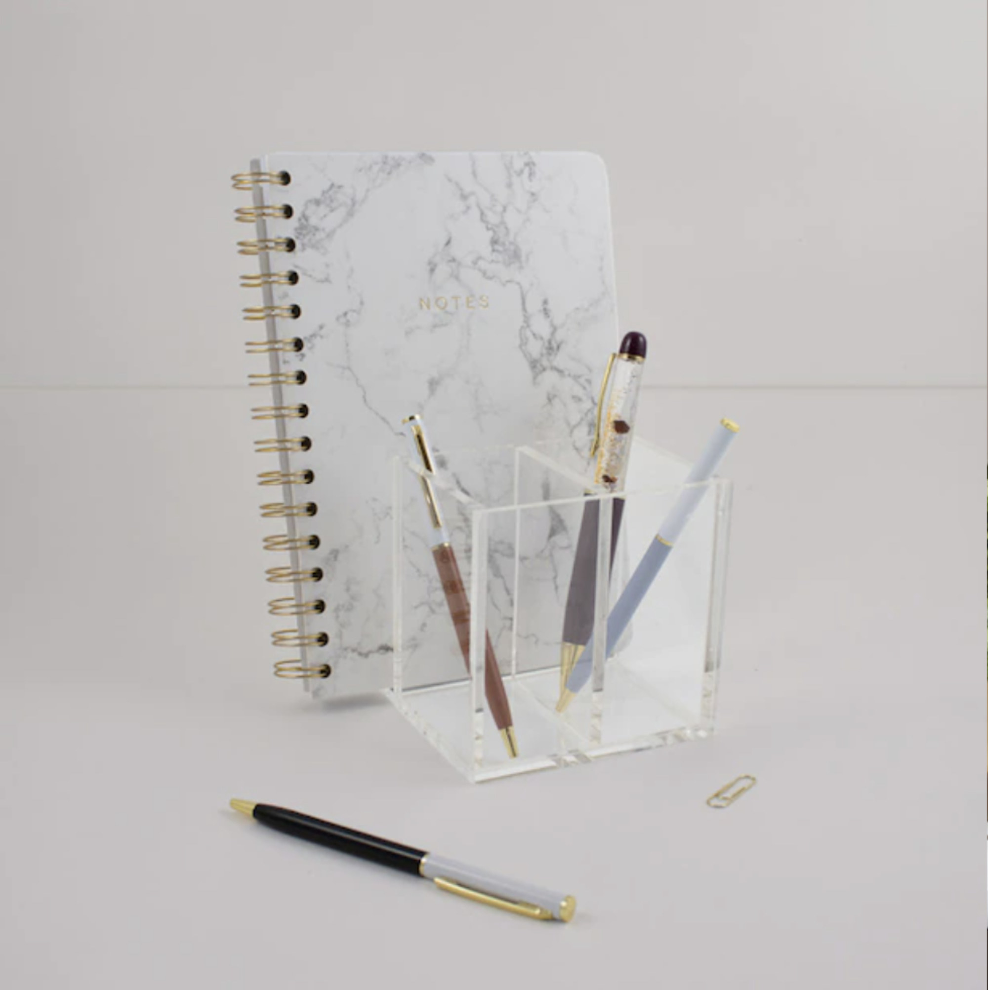 A square acrylic pencil holder with pens inside of it