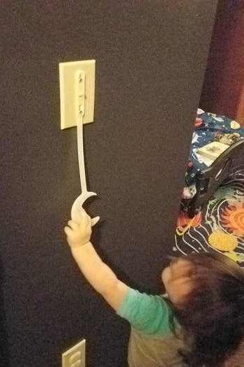 Reviewer's photo of a child reaching for the light switch extender