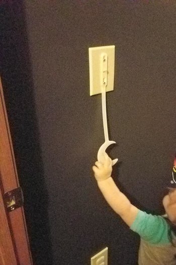 Reviewer's child reaching for the light switch extender