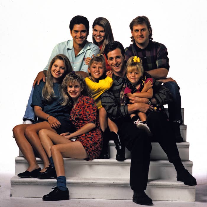 John Stamos, Lori Loughlin, Dave Coulier; Candace Cameron, Andrea Barber, Jodie Sweetin, Bob Saget, and one of the Olsen twins pose in a promotional photo for Full House