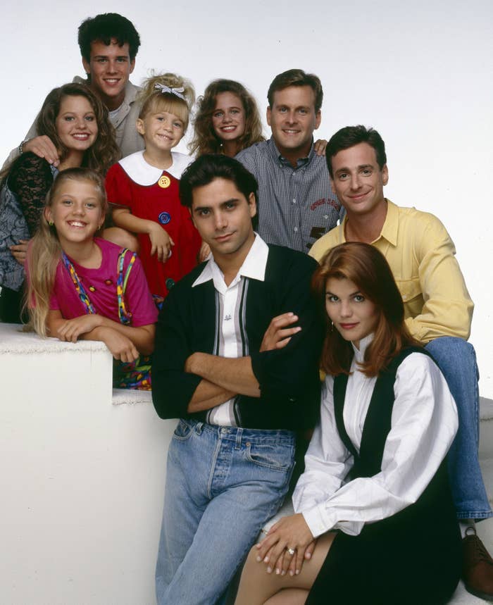 Jodie Sweetin, Candace Cameron, Scott Weinger, Mary-Kate Olsen/Ashley Olsen, Andrea Barber, John Stamos, Dave Coulier, Bob Saget, and Lori Loughlin pose in a promotional photo for Full House
