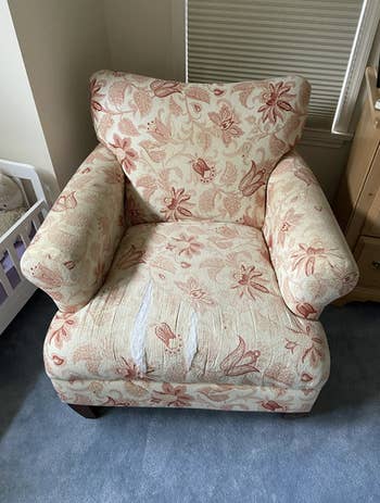 arm chair with ripped seat cushion and ugly floral print