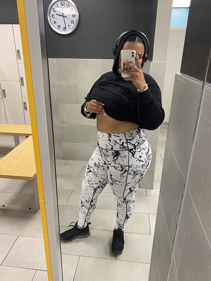 Reviewer is wearing the white leggings with black marbling pattern, black sneakers, and a black hoodie