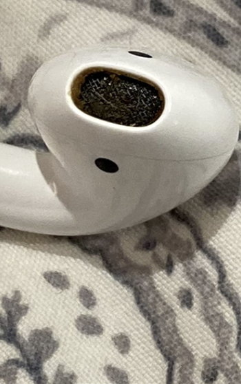 reviewer's AirPod speaker with built up earwax