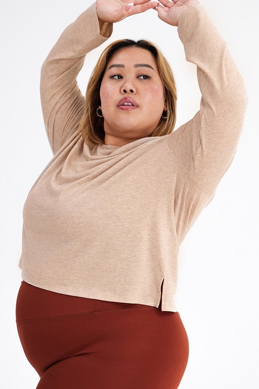 Model is wearing a sand-colored long sleeve tee with a clay-colored pair of exercise shorts