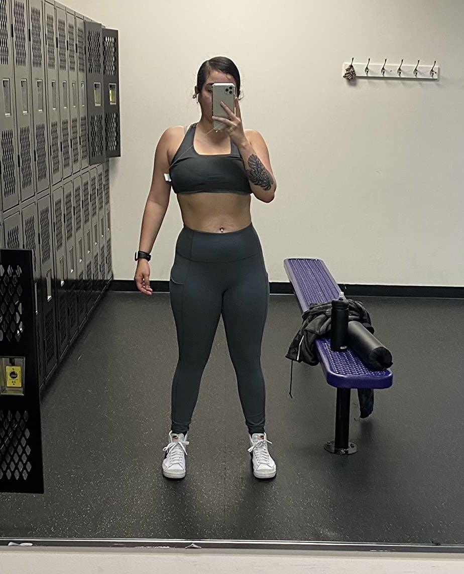 Reviewer is wearing grey leggings, white sneakers, and a grey sports bra