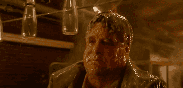 John Goodman as Ocious P. Potter covered in wet cheese in a dairy factory, as a conveyor line of empty milk bottles hit him over the head