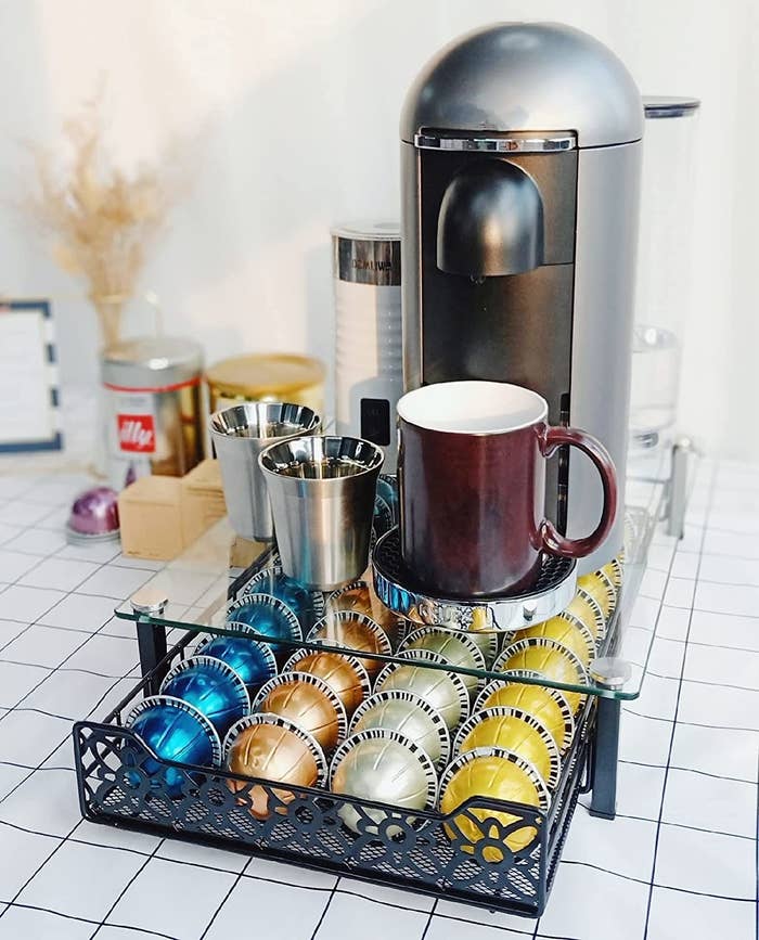 The organizer filled with pods with a coffee maker on top of it