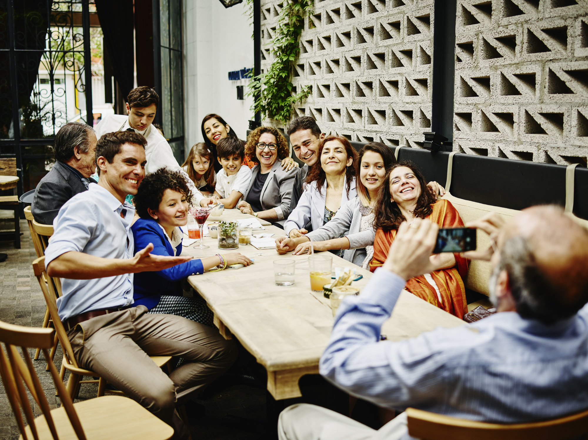 Man taking family portrait with smartphone during dinner party in restaurant