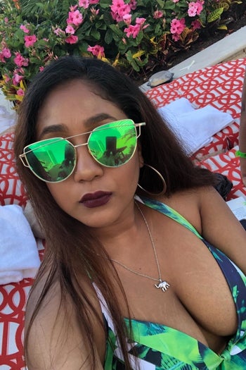 A reviewer wearing the sunglasses in gold with green lenses