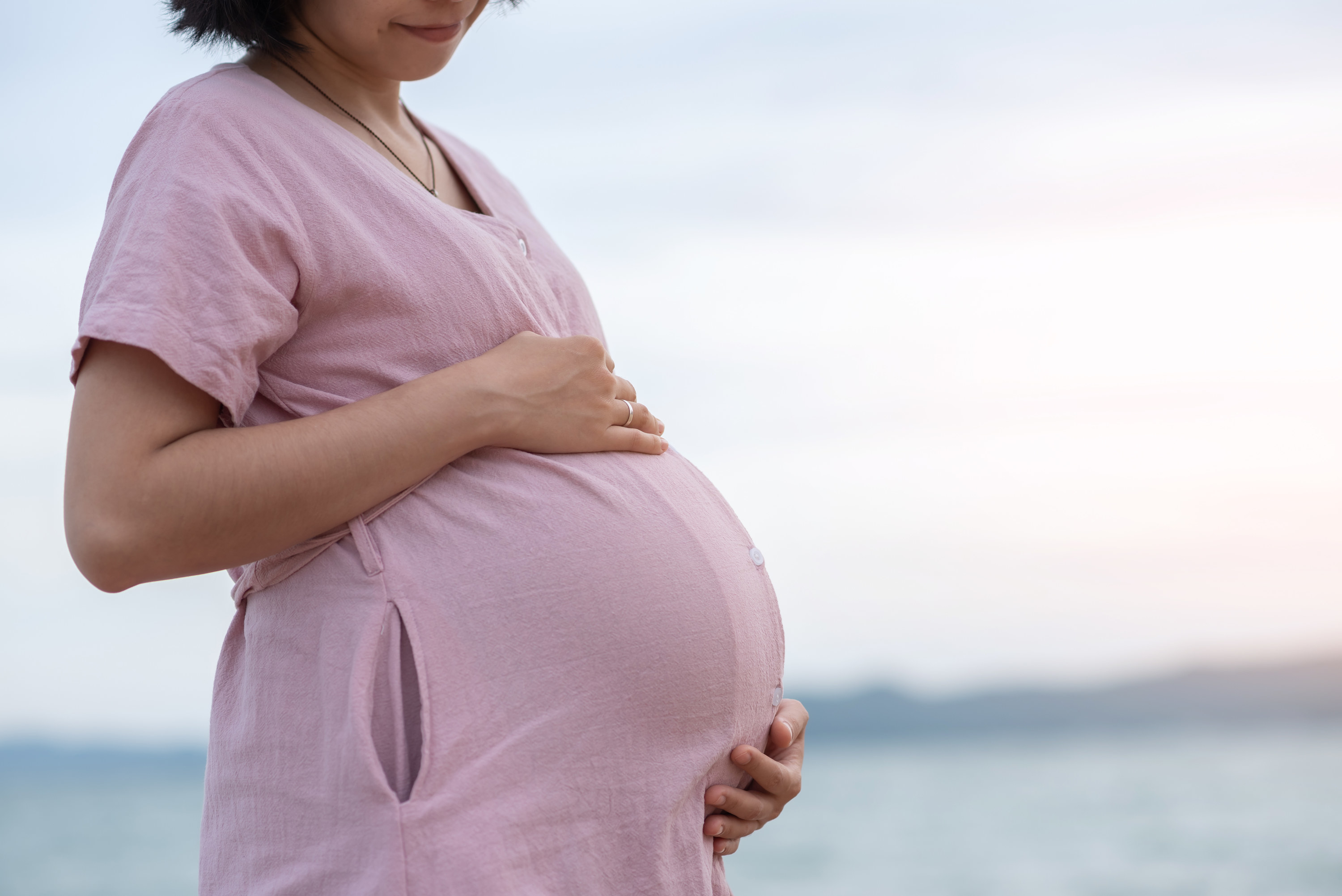 A pregnant Asian woman holding her stomach