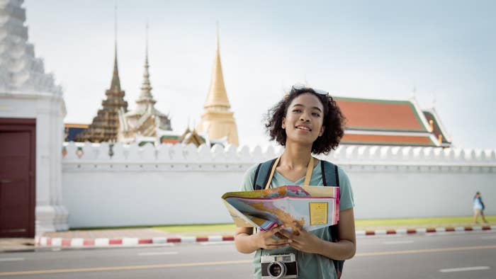 Tourist exploring Bangkok, Thailiand while holding map in front of Wat Phra Kaew temple