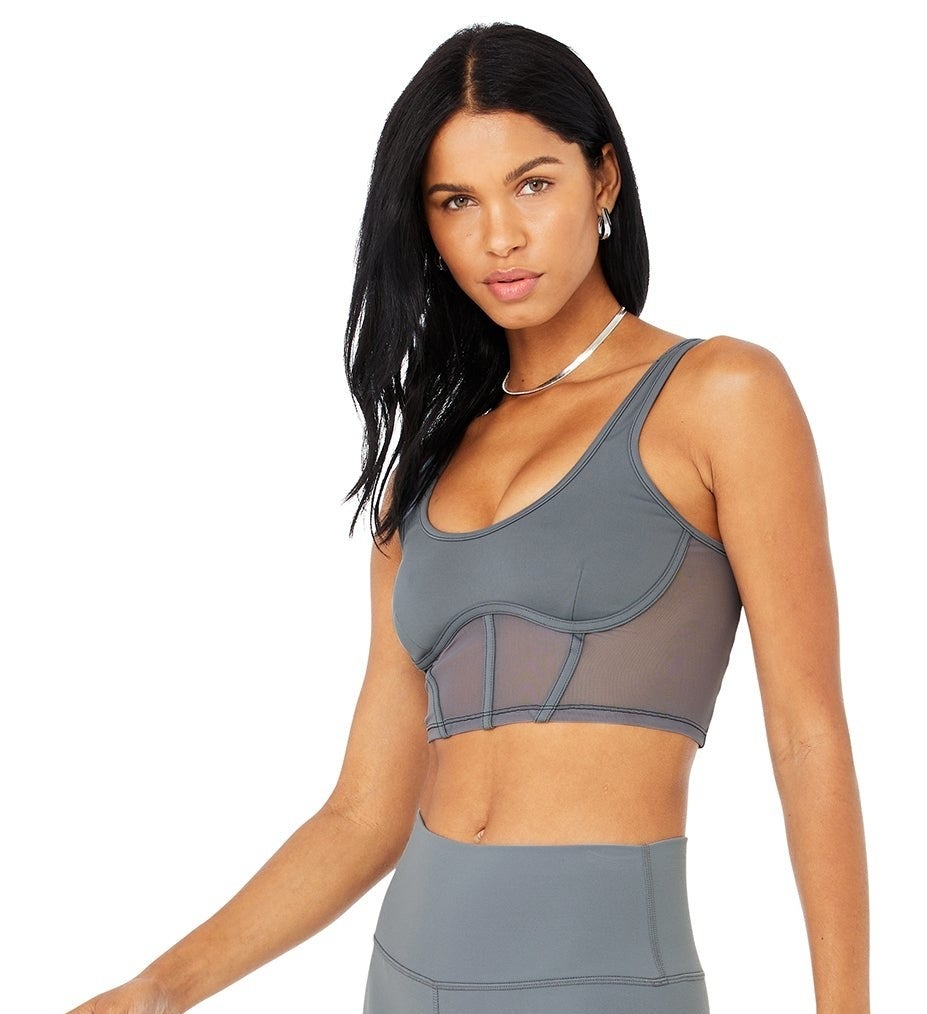 Model is wearing a grey mesh corset sports bra with exposed boning