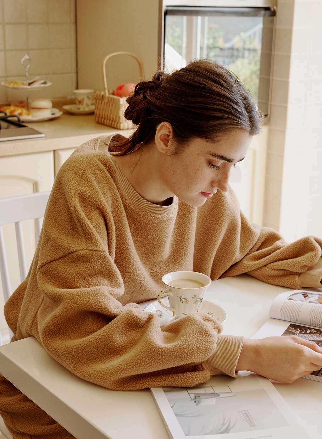 a person wearing the fuzzy sweatshirt while sipping coffee at a dining table