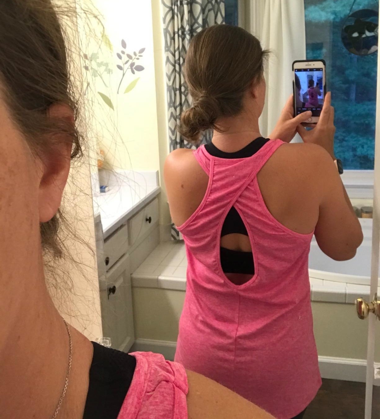 Reviewer is wearing a hot pink tank top with a criss cross peep hole back