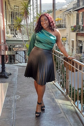 A reviewer wearing the balloon sleeve bodysuit in emerald green, tucked into a skirt