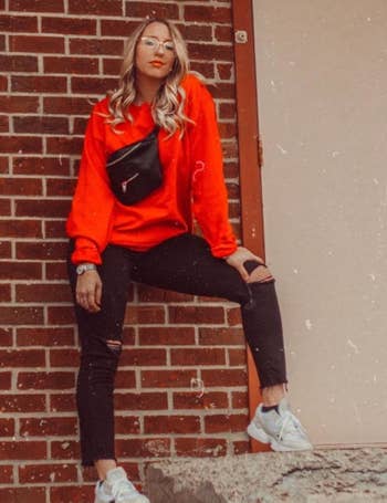 reviewer wearing the red crewneck with black pants and sneakers
