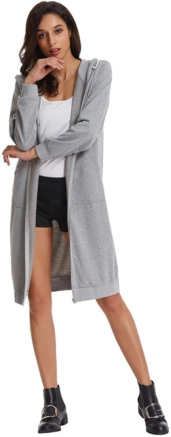 model wearing the long gray sweatshirt with the hood down