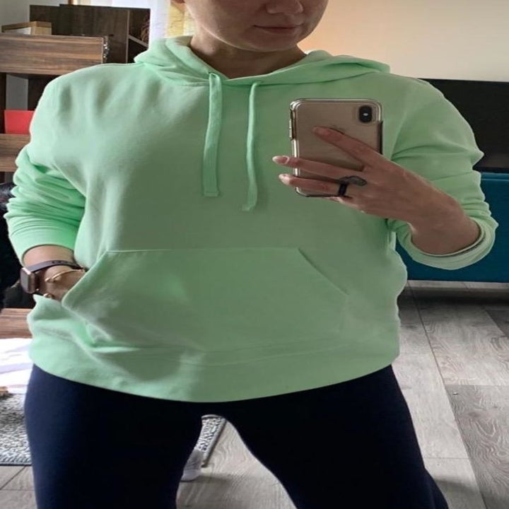 reviewer wearing the light green hoodie