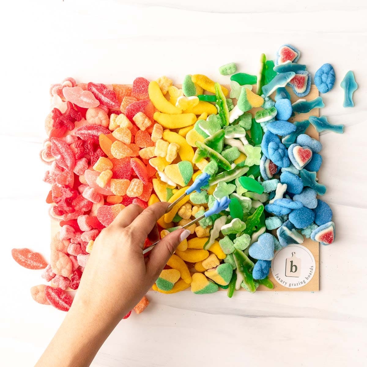 Hand reaching for rainbow candy from assortment on a baord