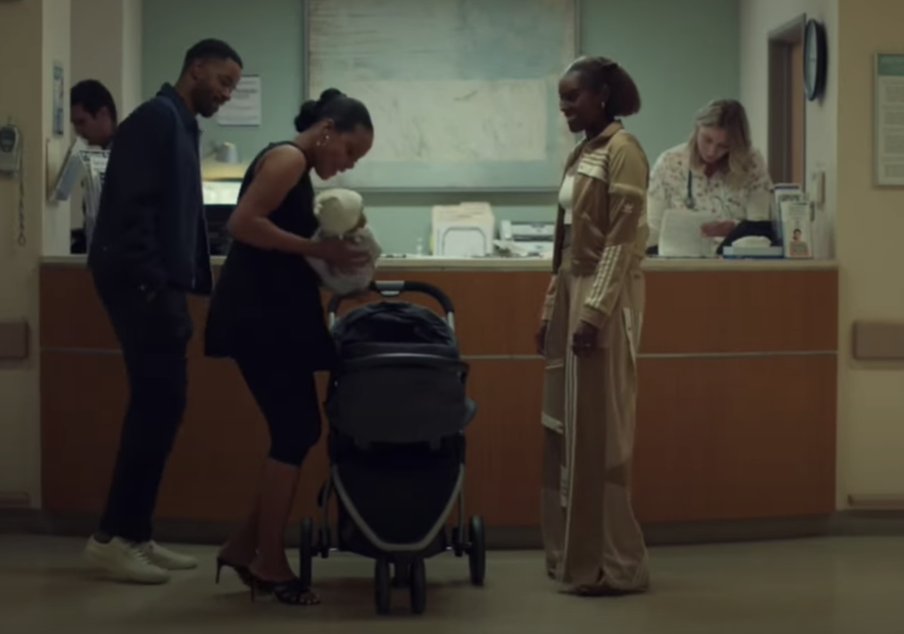 Three people in the hospital looking at a baby