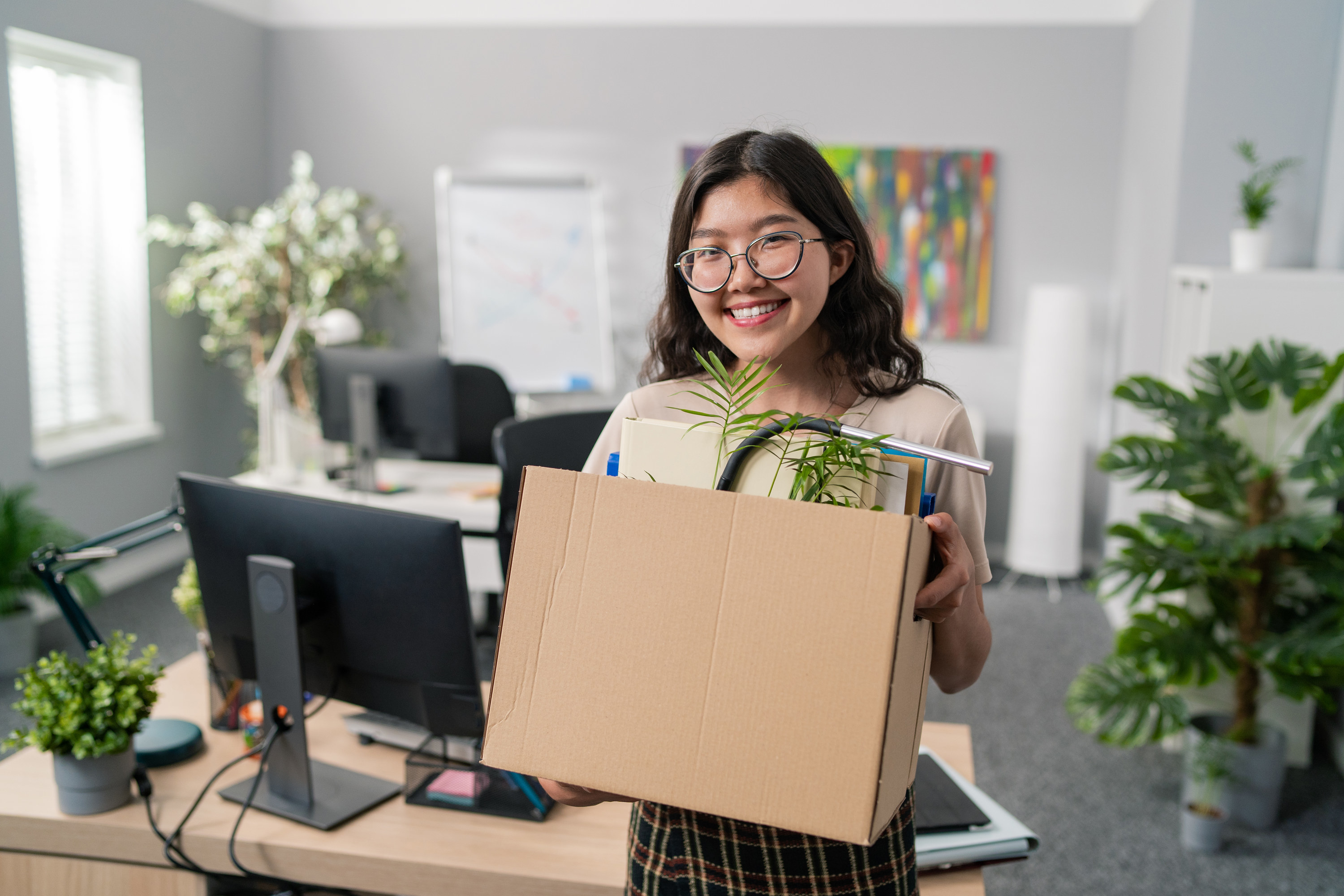 Woman smiling and carrying a box of her stuff out of an office