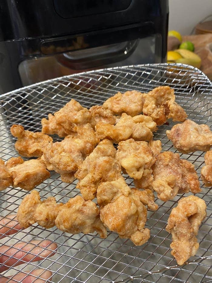 Breaded chicken pieces going into an air fryer.