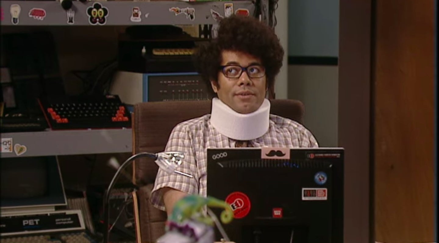 Moss with a neck brace sitting at his laptop in &quot;The IT Crowd&quot;