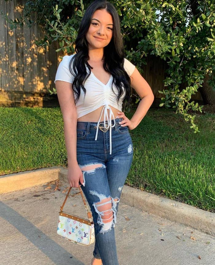Jasmine posing for a photo in a crop top, ripped jeans, and a Louis Vuitton purse
