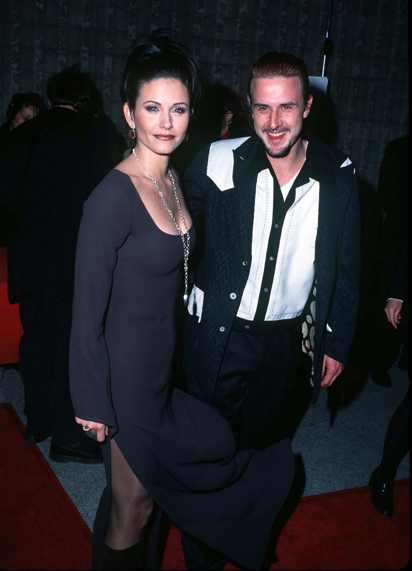 Courteney Cox in a long-sleeved gray dress and David Arquette in a black suit with white trim