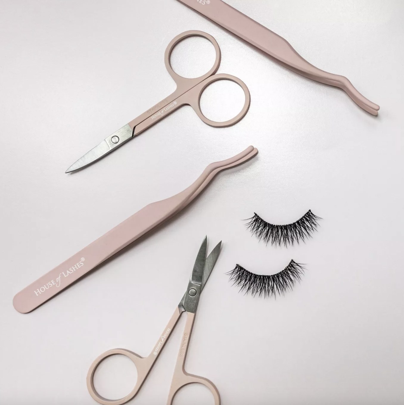 A pair of eyelash tools, scissors, and false eyelash strips