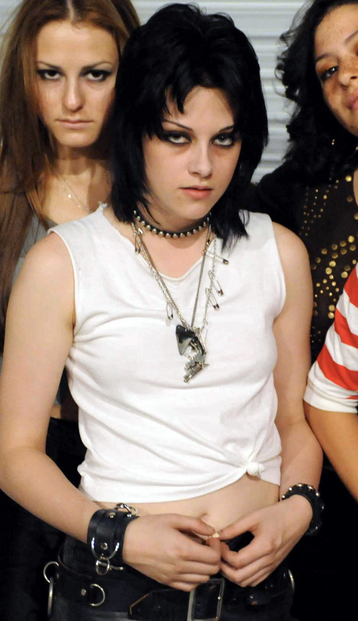 Stewart posing in a white tank top and black, leather jewelry
