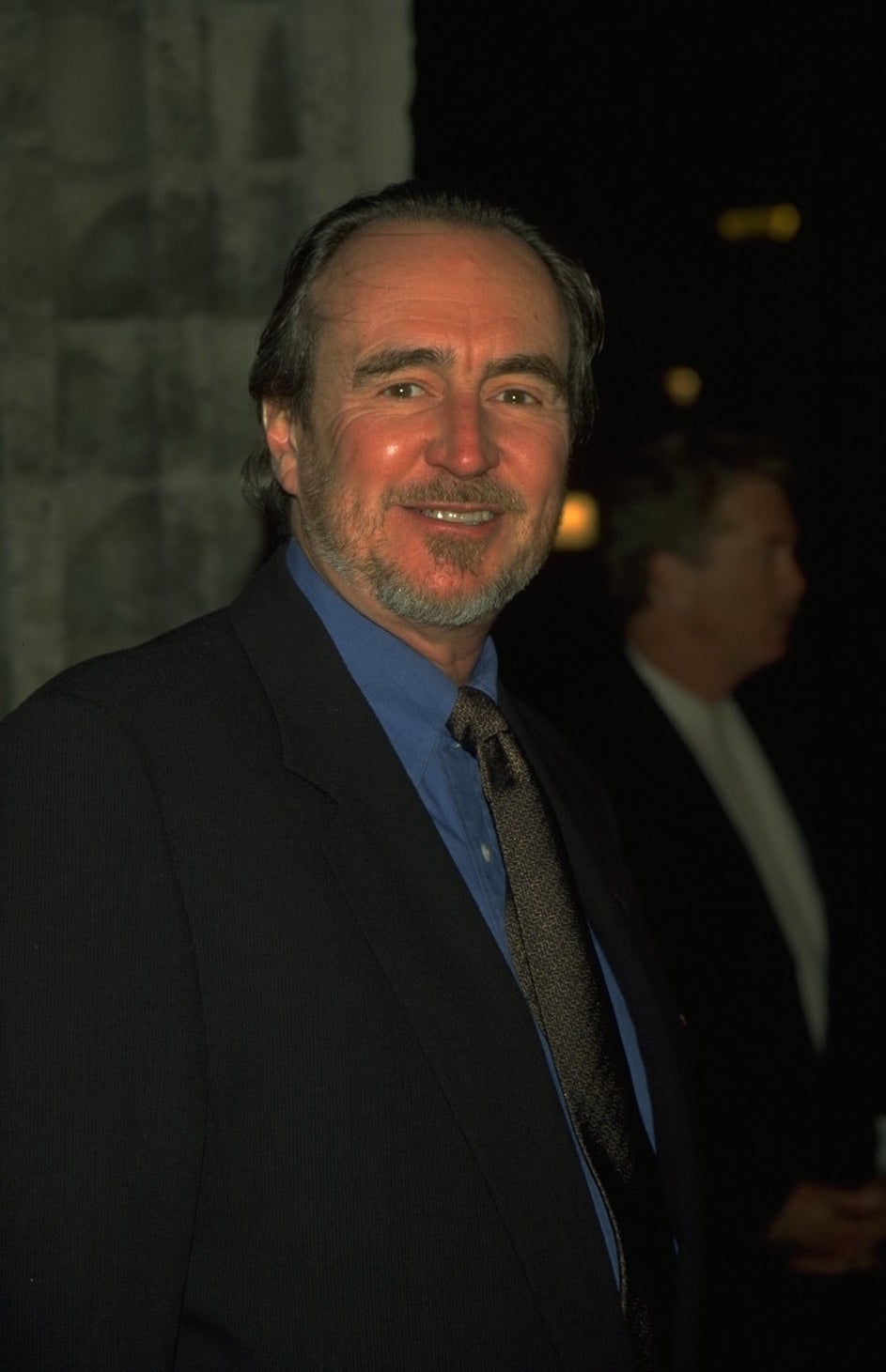 Wes Craven in a black suit with a blue shirt and black tie