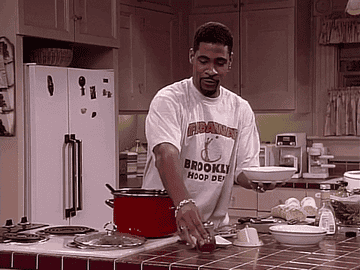 John Henton as Obie Wakefield Jones stands over a pot in the kitchen and holds a bowl as he slowly shakes seasoning into the bowl in &quot;Living Single&quot;