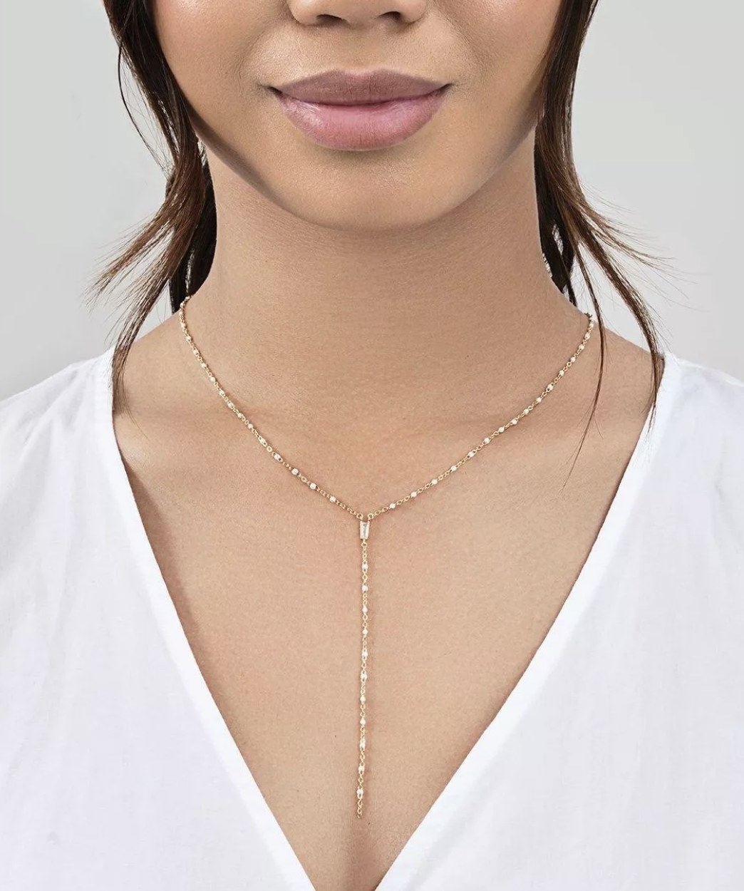 a y-shaped necklace with white beads and gold links