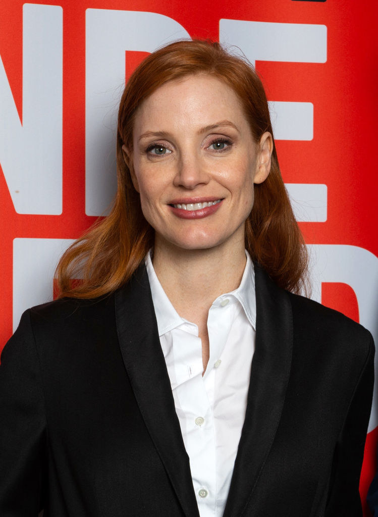 Chastain dressed in a black suit jacket and white shirt on the red carpet
